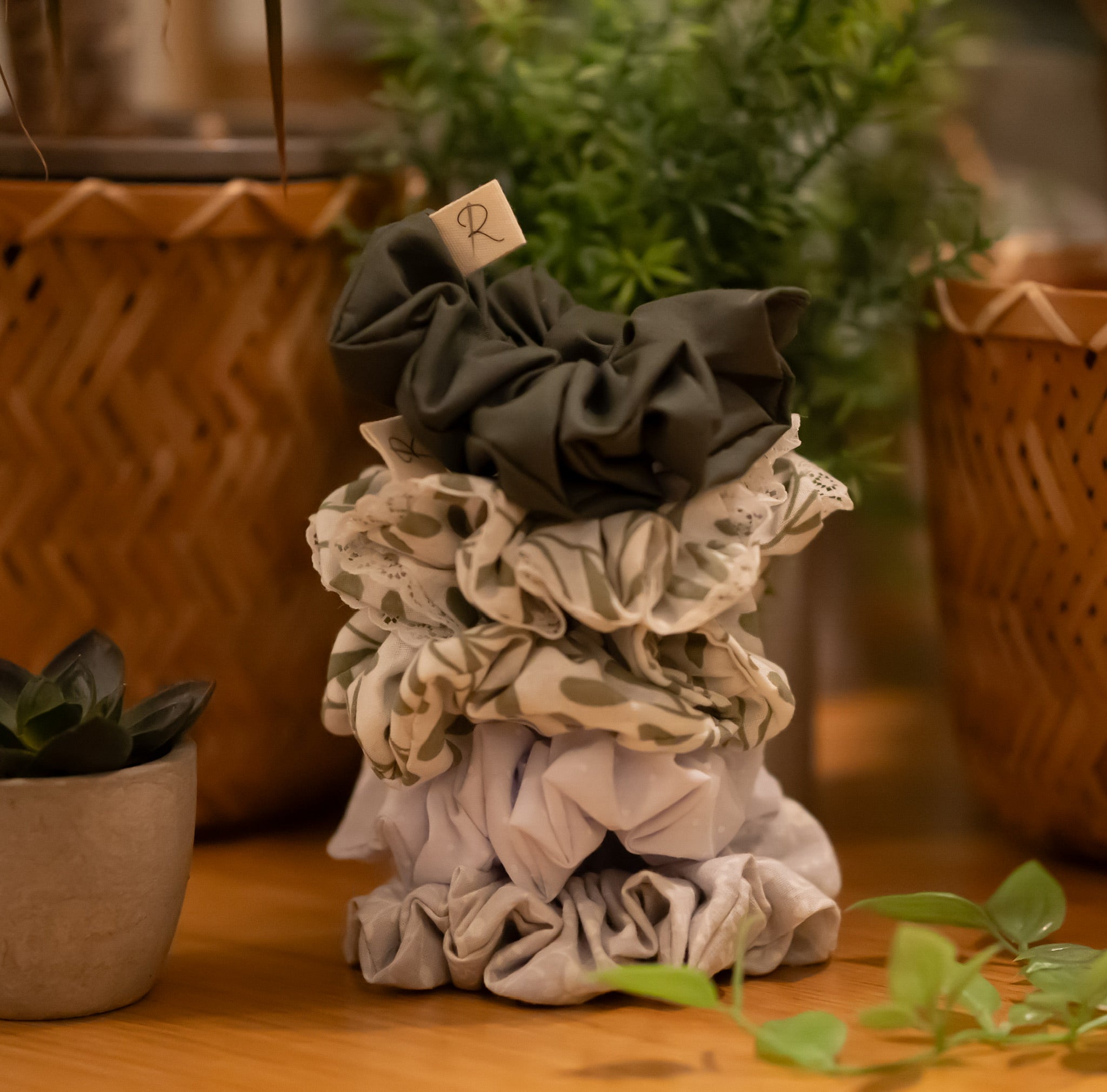 A stack of scrunchies on a wooden surface with plants in the background