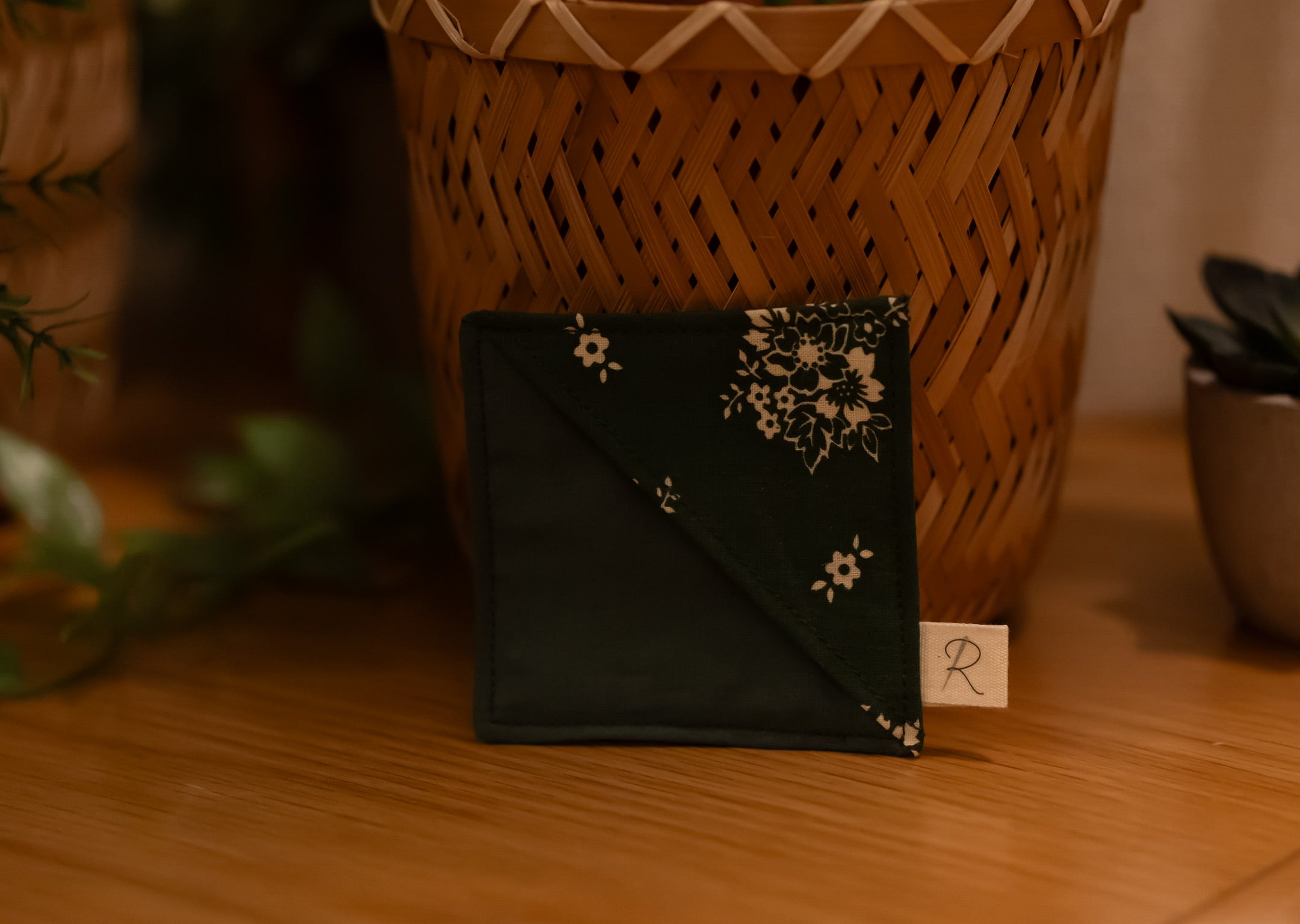 Green bookmark with floral design on a wooden surface with a blurred background