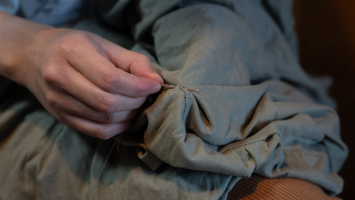 Close-up of a person's hand holding a piece of fabric with a needle.