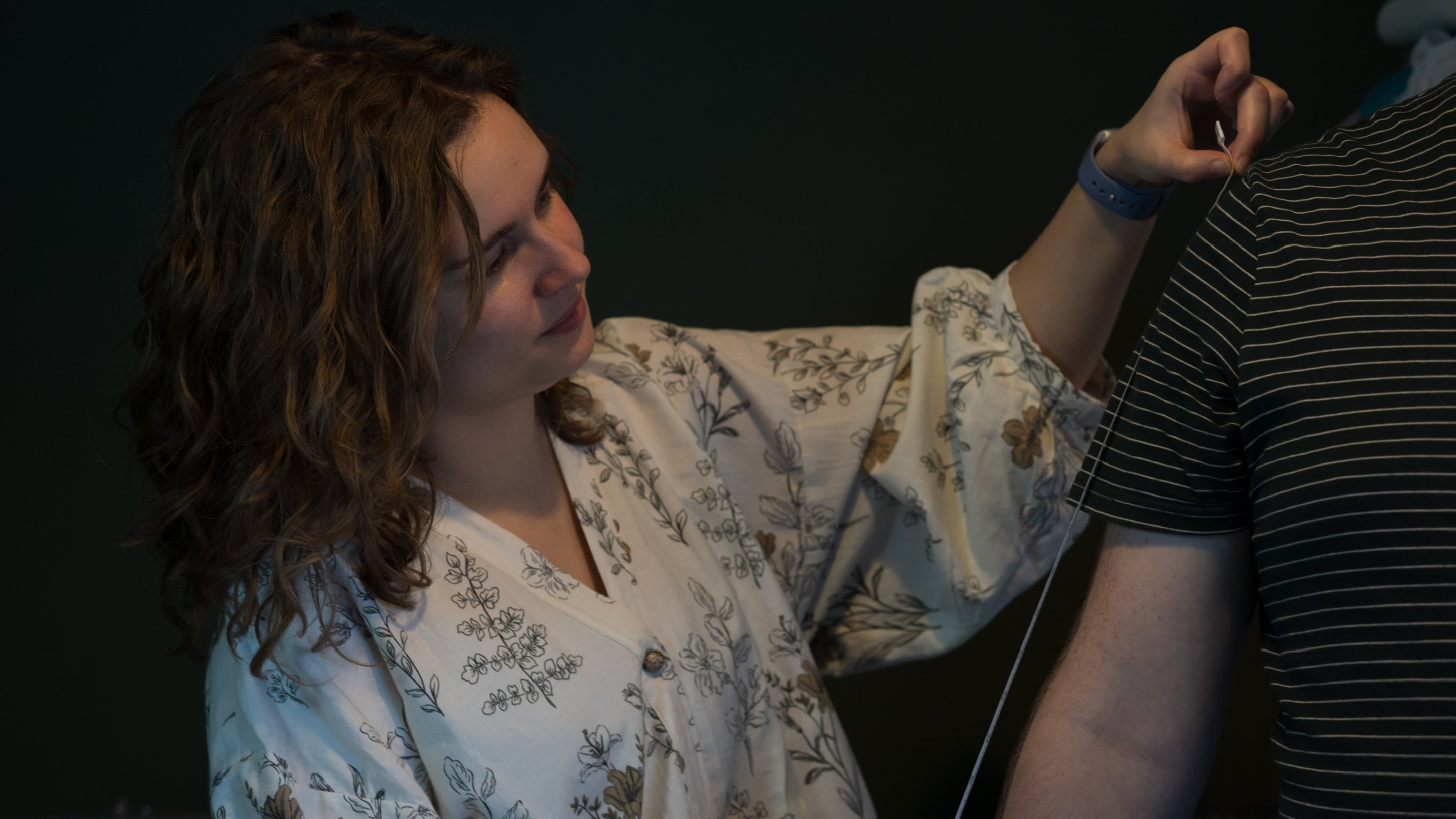 Woman measuring the arm of a man wearing a striped tshirt