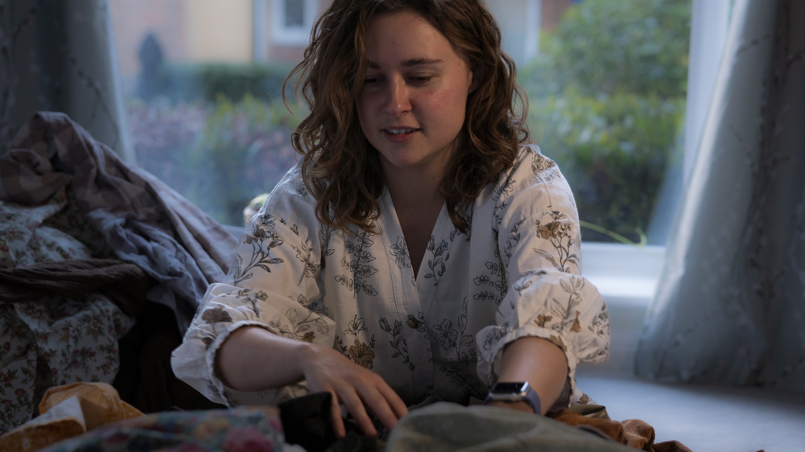Woman searching through a pile of clothes on the floor