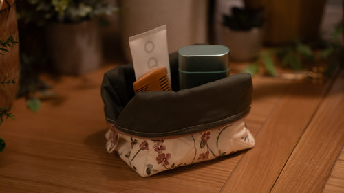 Small boxy bag with cosmetic items on a wooden surface