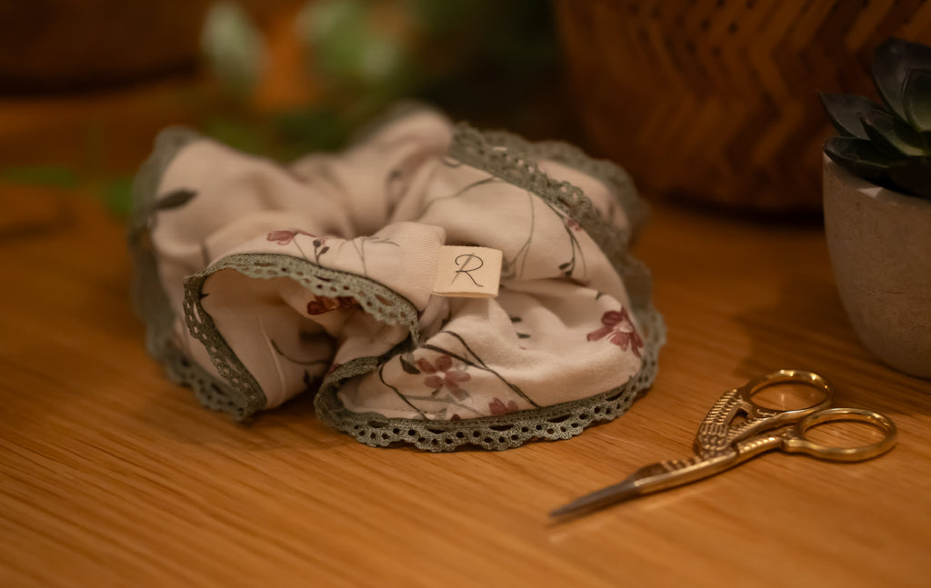 Scrunchie with floral pattern on a wooden surface with a pair of scissors.