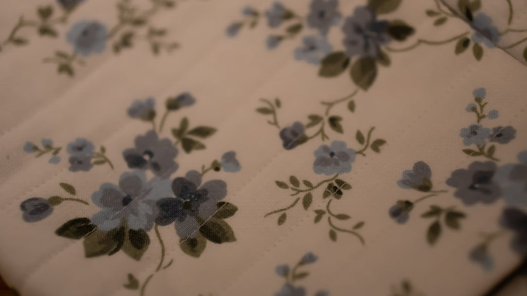 Close up of floral pattern with blue flowers and green leaves.