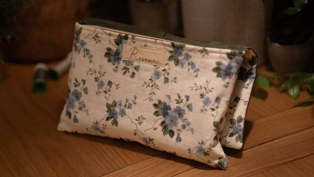 Floral-patterned book sleeve with 'Resewn' branding on a wooden surface