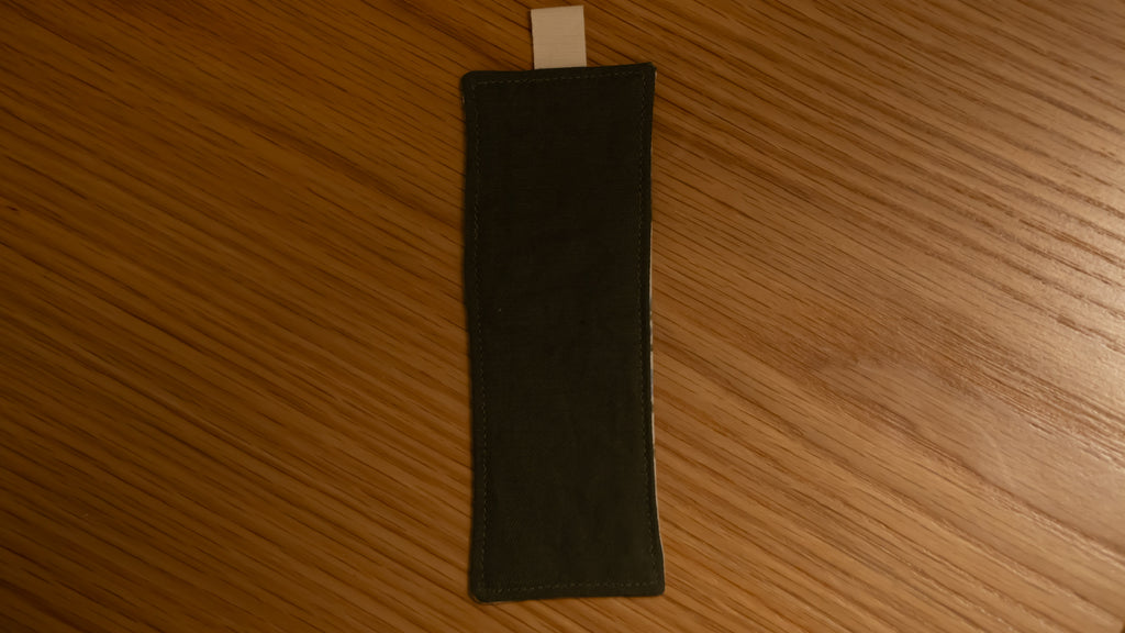 Dark green rectangular bookmark on a wooden surface