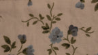 Floral patterned fabric close up with blue flowers and green leaves