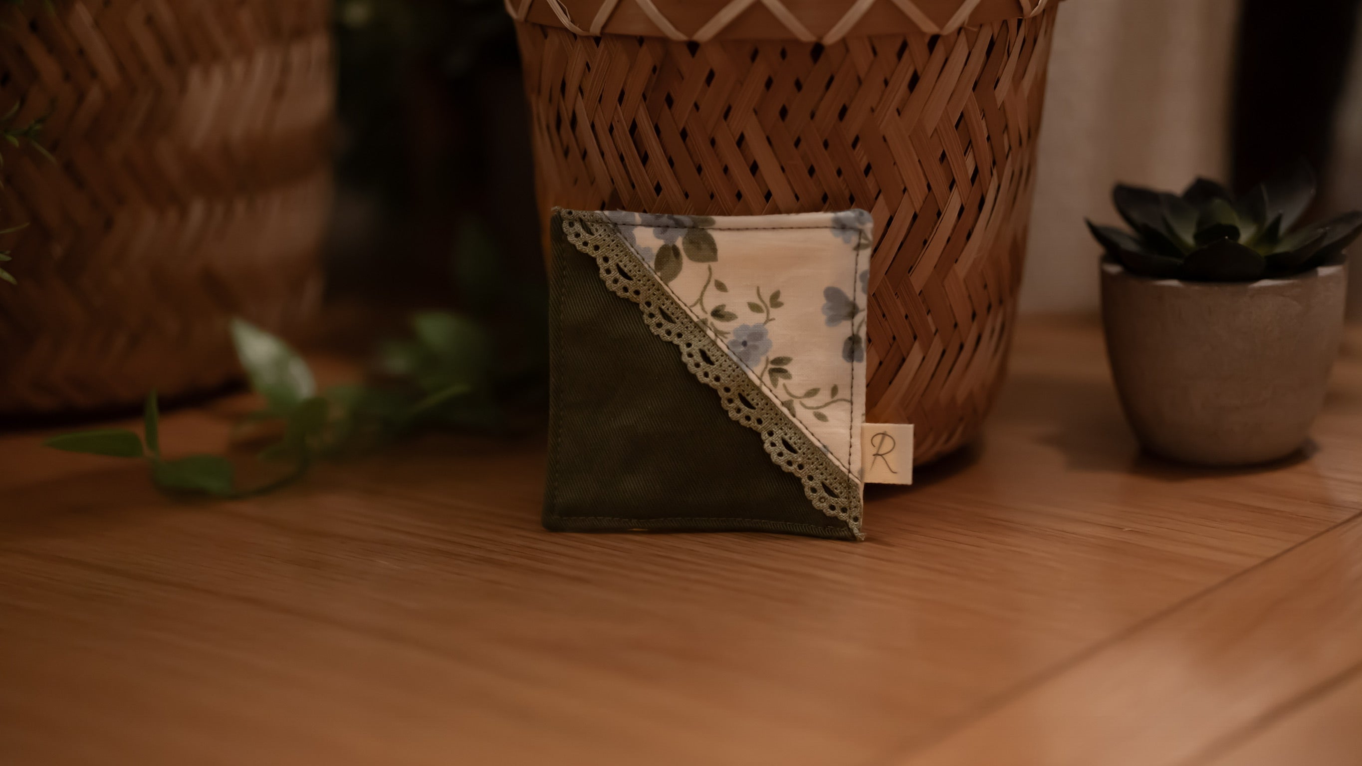 Square bookmark with floral pattern on a wooden surface with plants in the background