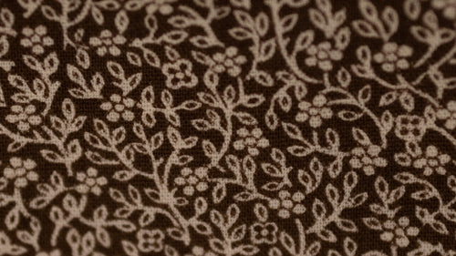 Close-up of brown fabric with subtle floral pattern
