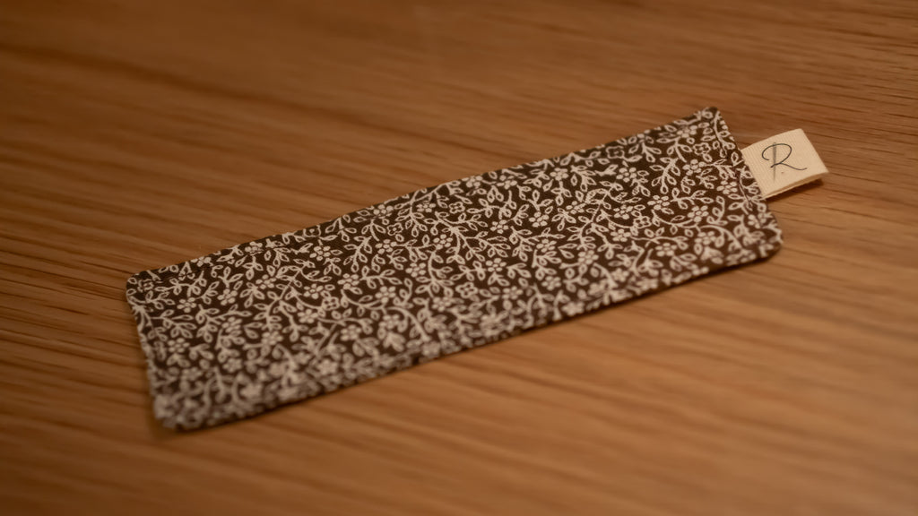Floral-patterned bookmark on a wooden surface with a visible brand tag.
