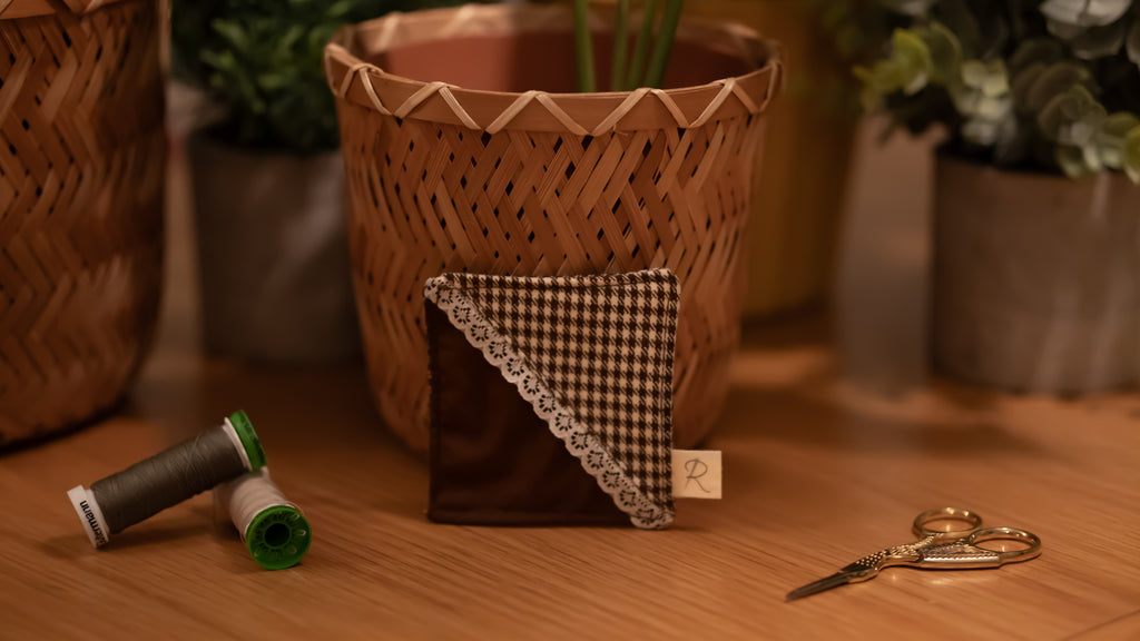 Fabric bookmark with checkered pattern on a wooden surface with thread and scissors