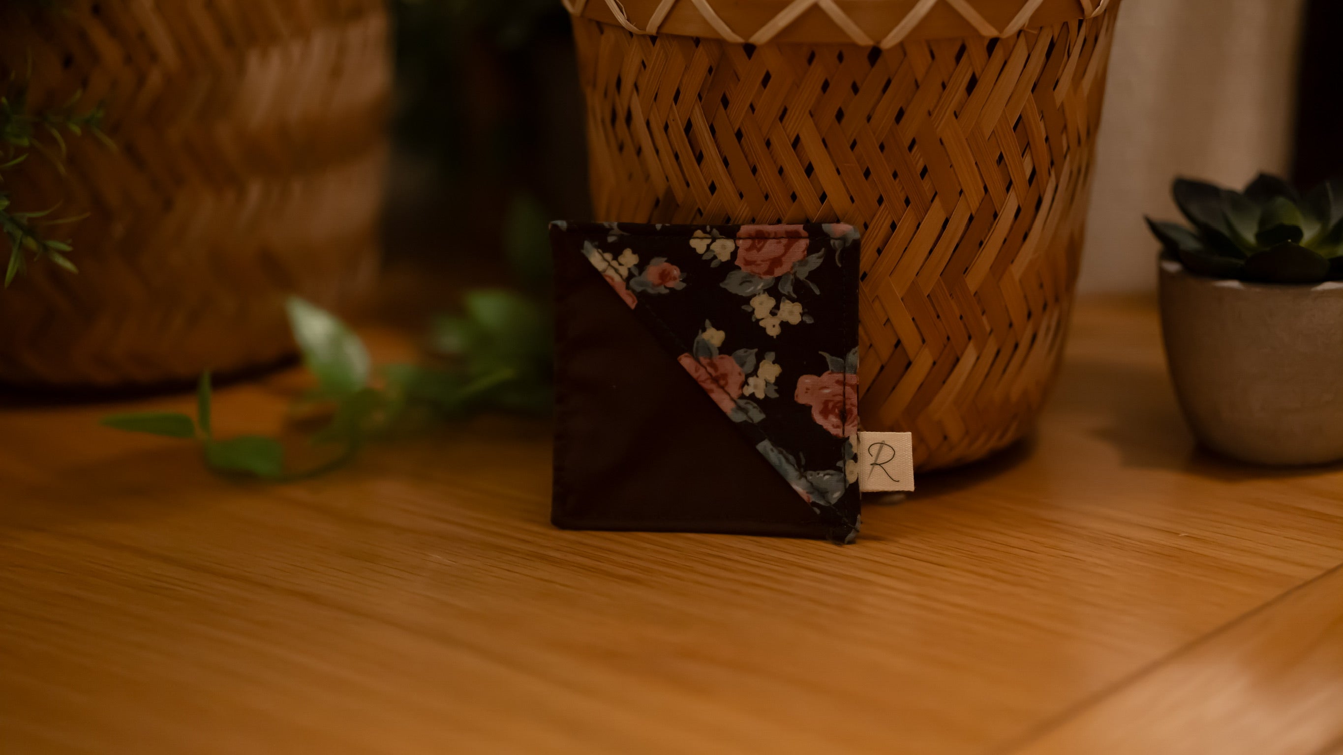 Floral bookmark on a wooden surface with plants in the background
