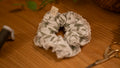 Scrunchie with leaf pattern and lace edge on a wooden surface