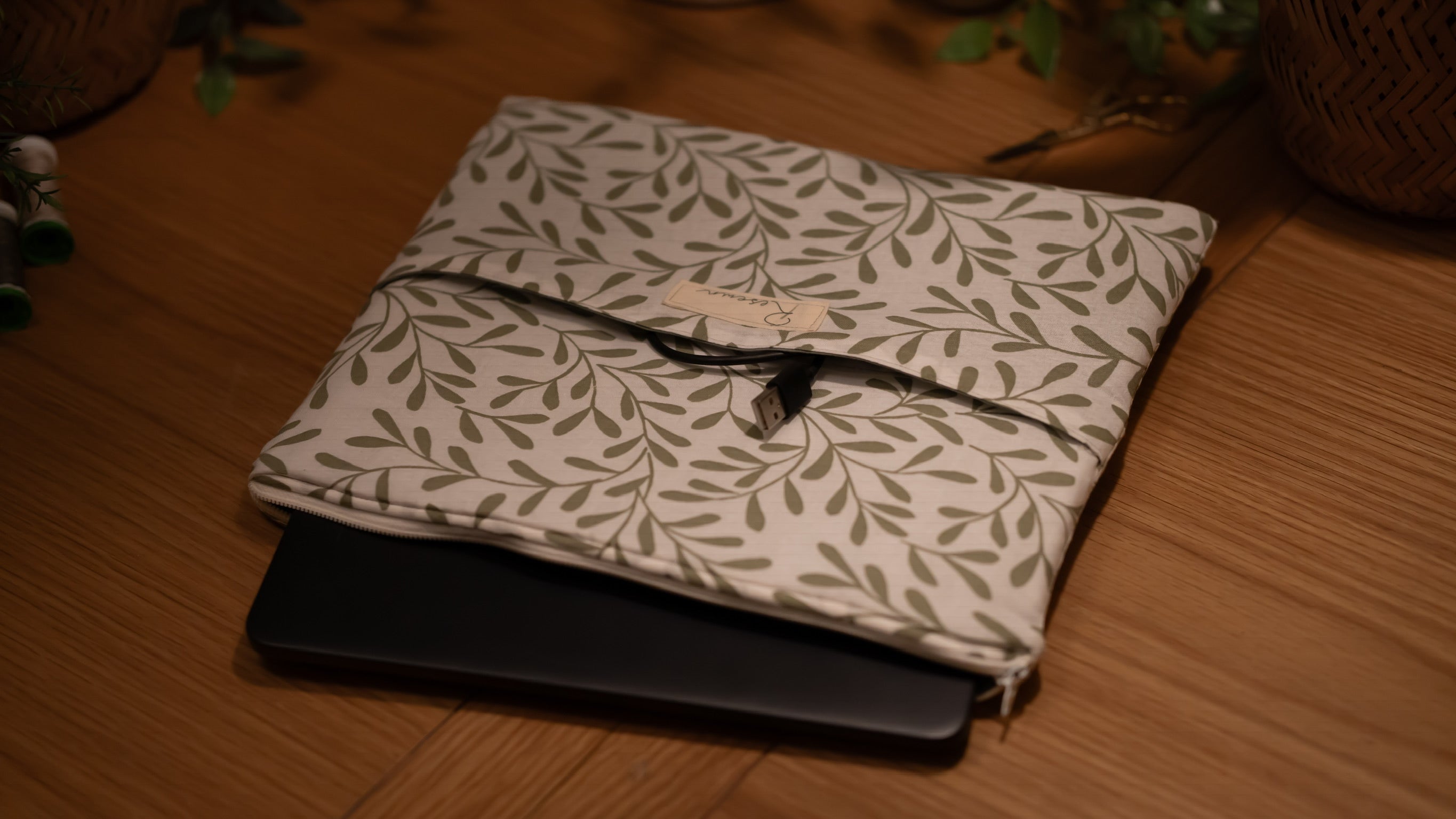 Folded leaf-patterned fabric sleeve with a laptop sticking out on a wooden surface
