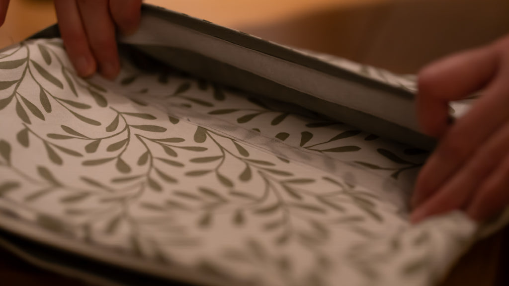 Person fabric to show velcro pocket with green leaves on a wooden surface