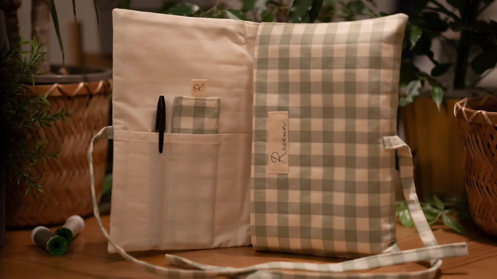 Fabric book sleeve with checkered pattern opened to show pockets on wooden surface