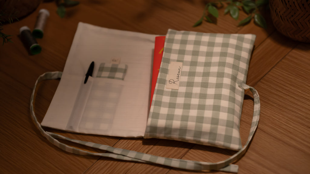 Fabric book sleeve with checkered pattern opened to show pockets on wooden surface