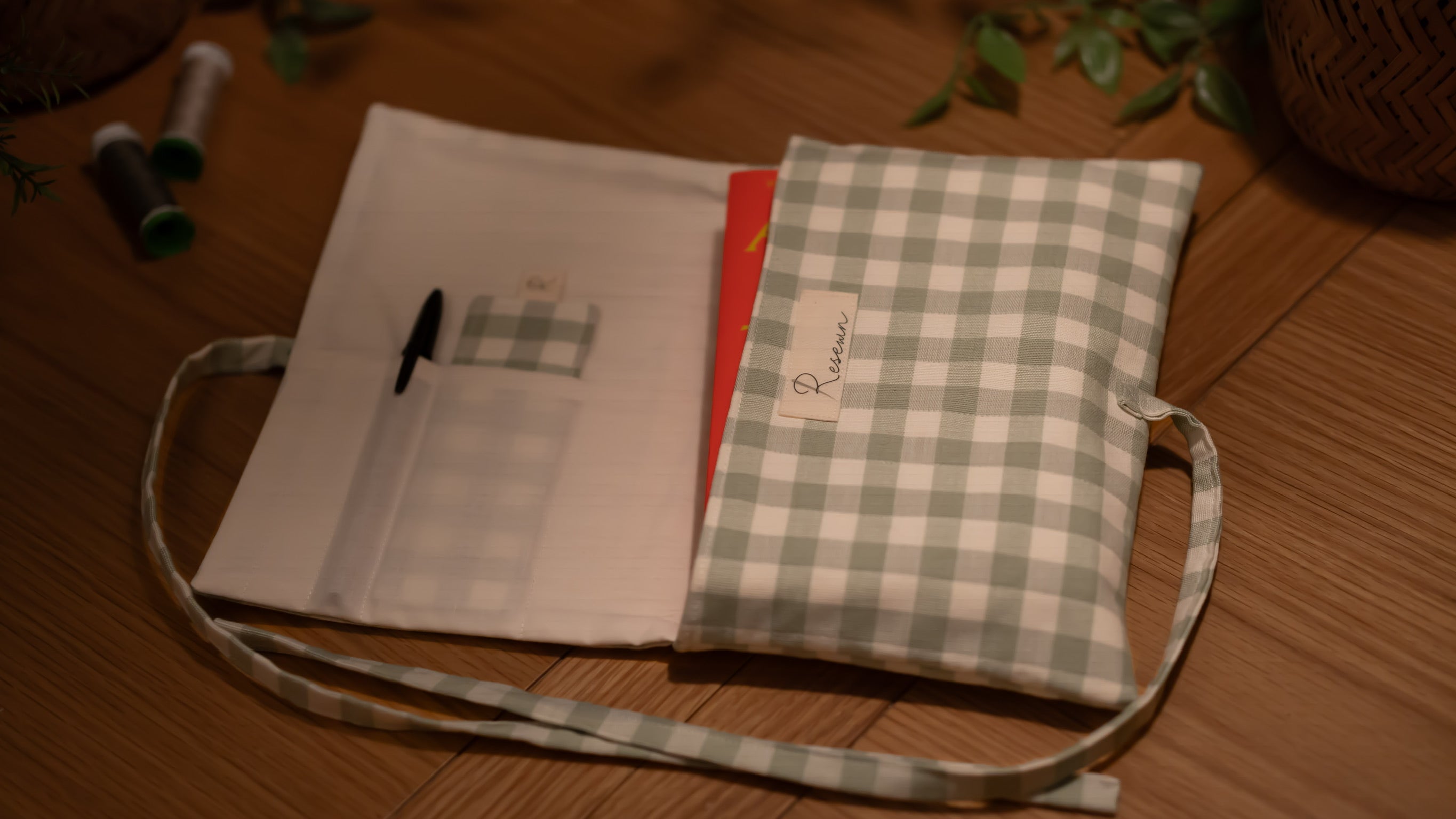 Fabric book sleeve with checkered pattern opened to show pockets on wooden surface
