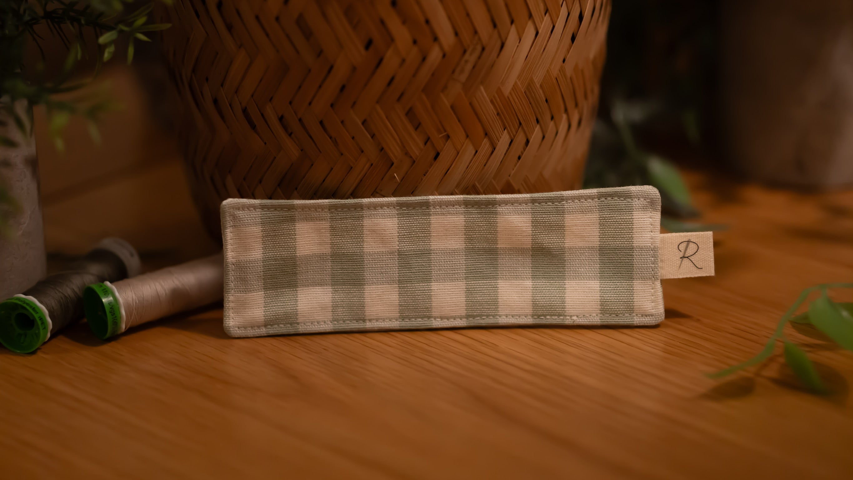 Checkered fabric bookmark with a brand tag on a wooden surface