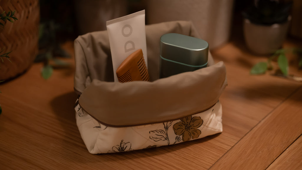 Fabric boxy bag opened with cosmetic items on a wooden surface