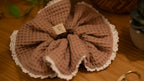 Pink textured scrunchie with a lace edge on a wooden surface