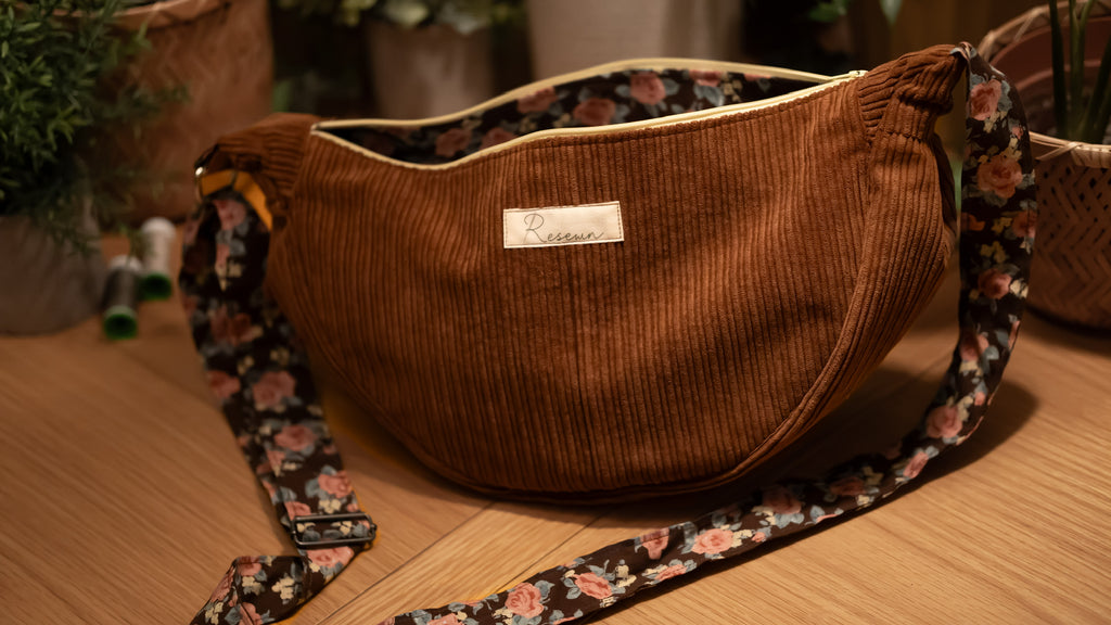 Brown corduroy bag with floral strap on a wooden surface