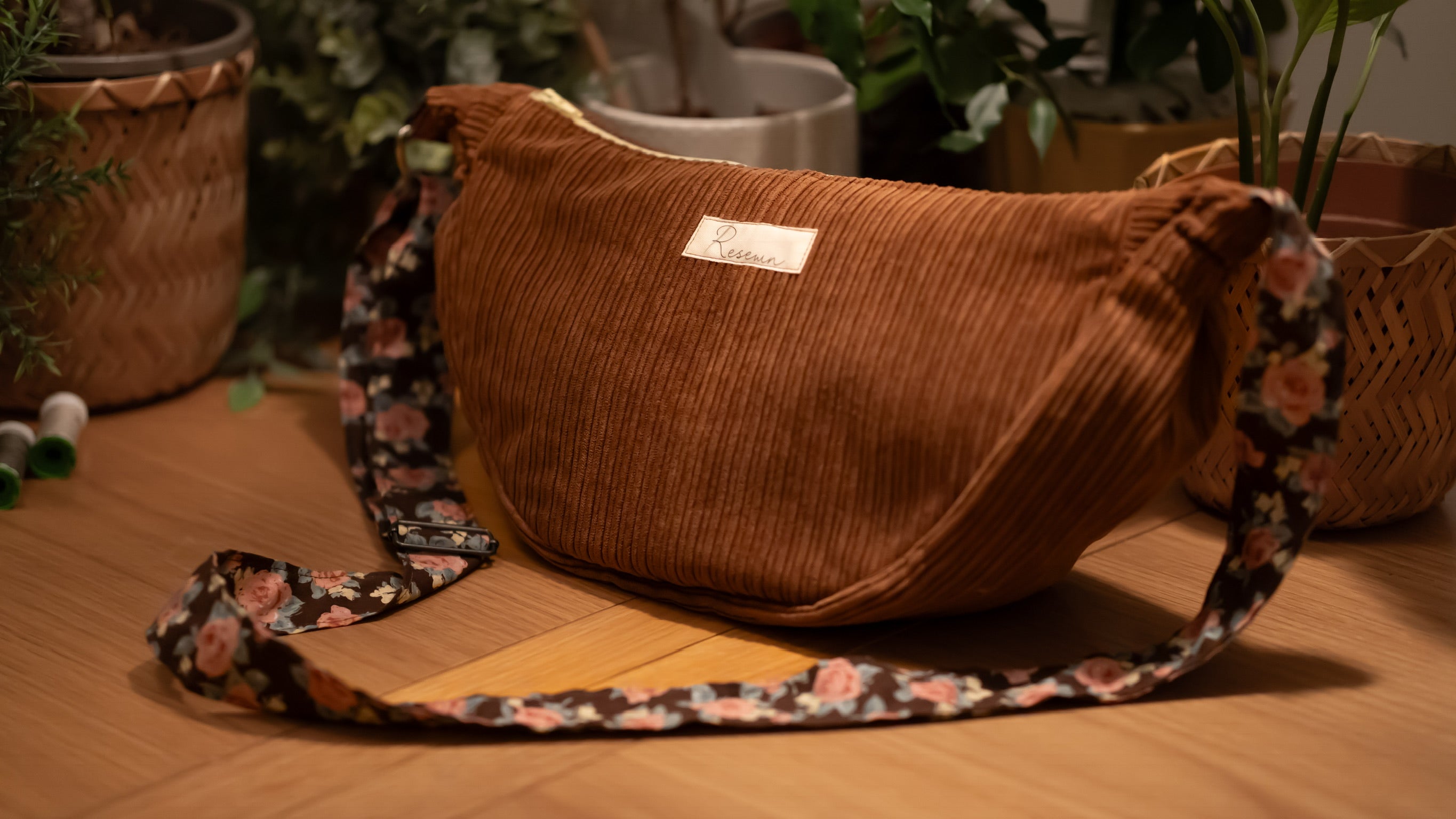 Brown corduroy bag with a floral strap on a wooden surface